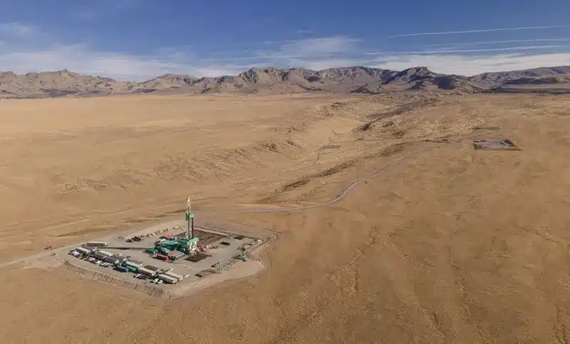 utah-forge-web_0 Aerial view of the Utah FORGE geothermal research site near Milford, Utah. The image shows a drilling rig and support equipment set in a vast, arid desert landscape, backed by distant mountains. This field lab is testing enhanced geothermal systems to expand clean energy access across the U.S.