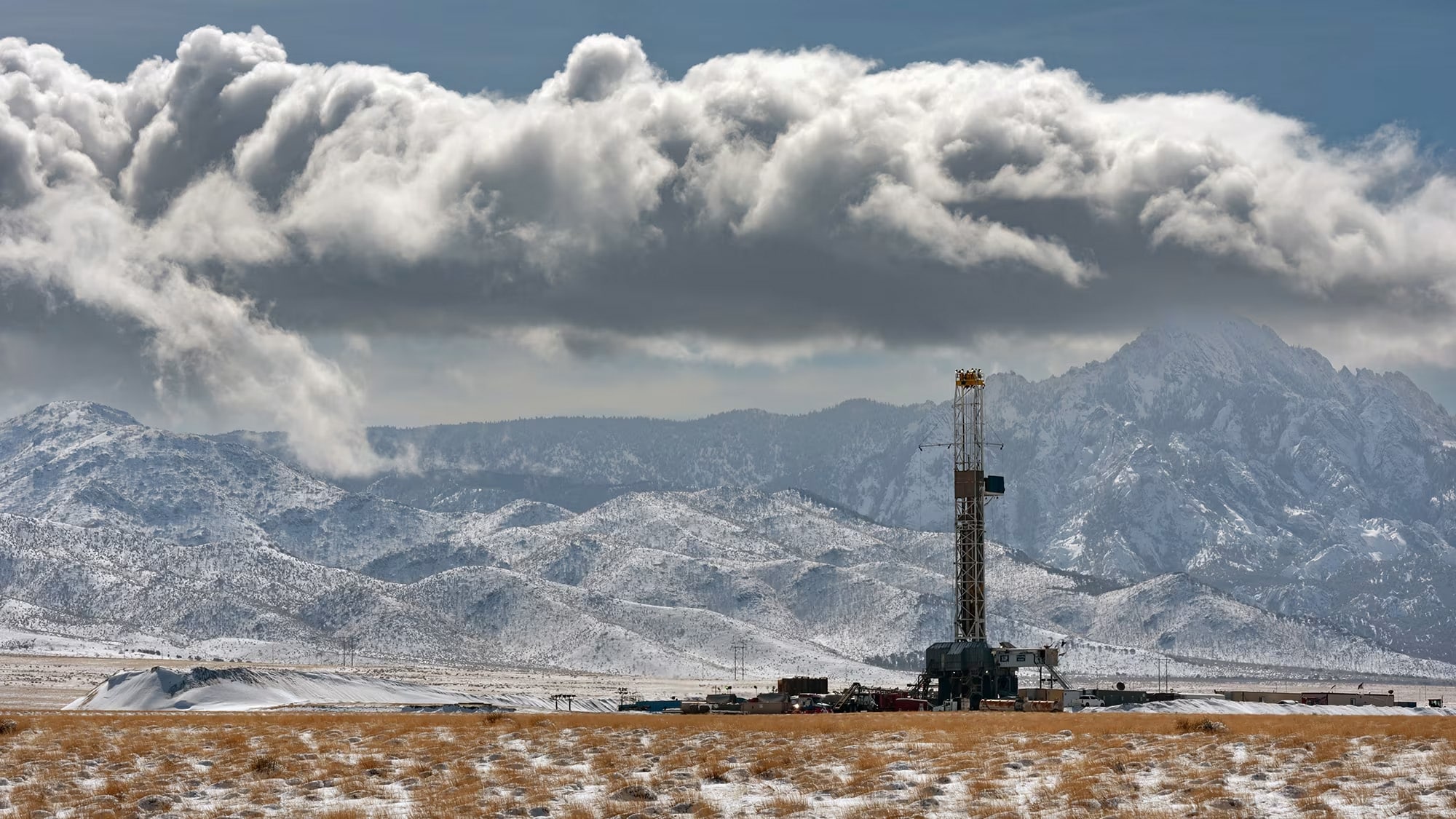 fervo-energy-cape-station-5 A worker stands beside drilling equipment at an enhanced geothermal project site in the Utah desert, surrounded by rocky terrain and clear blue sky. (Fervo Energy / CNN)